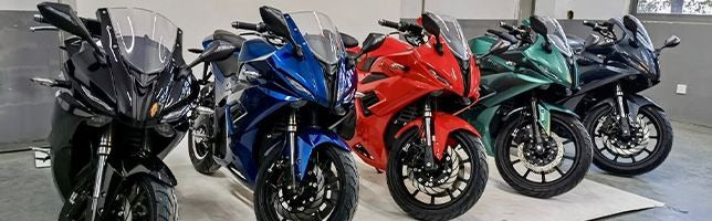 Sportmotorräder in verschiedenen Farben – schwarz, blau, rot und grün – Frontansicht schräg im Showroom